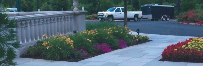 A white sidewalk showing built-in garden blocks with lush florals